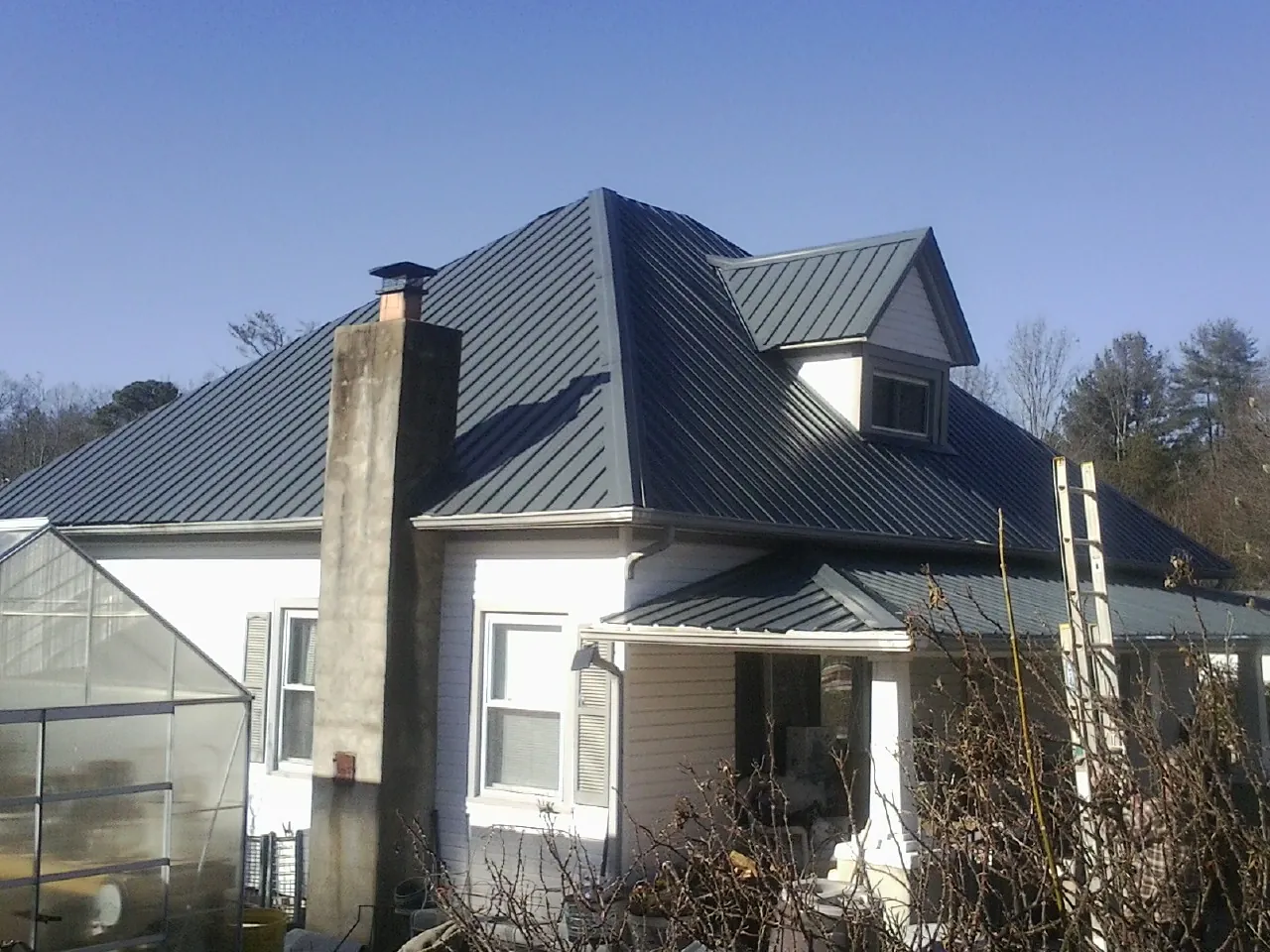 Dark blue standing seam metal roof on a white farmhouse with dormer — Slate & Tile Roof Repair by Roofing Brothers in Hagarville