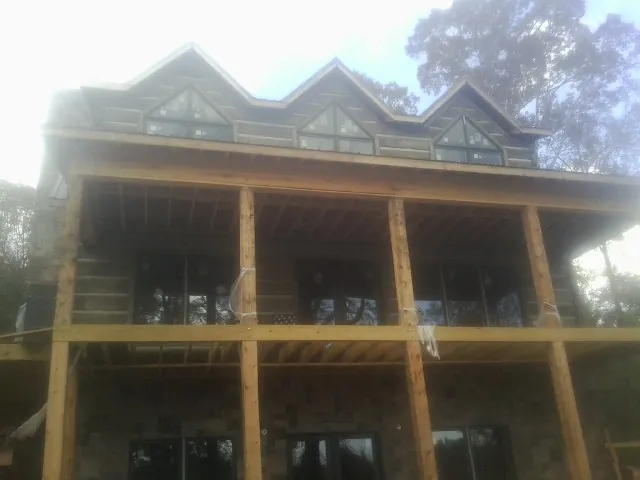 Dormers and porch framing on a large log home under construction — Roof Coating work by our crew in Hagarville