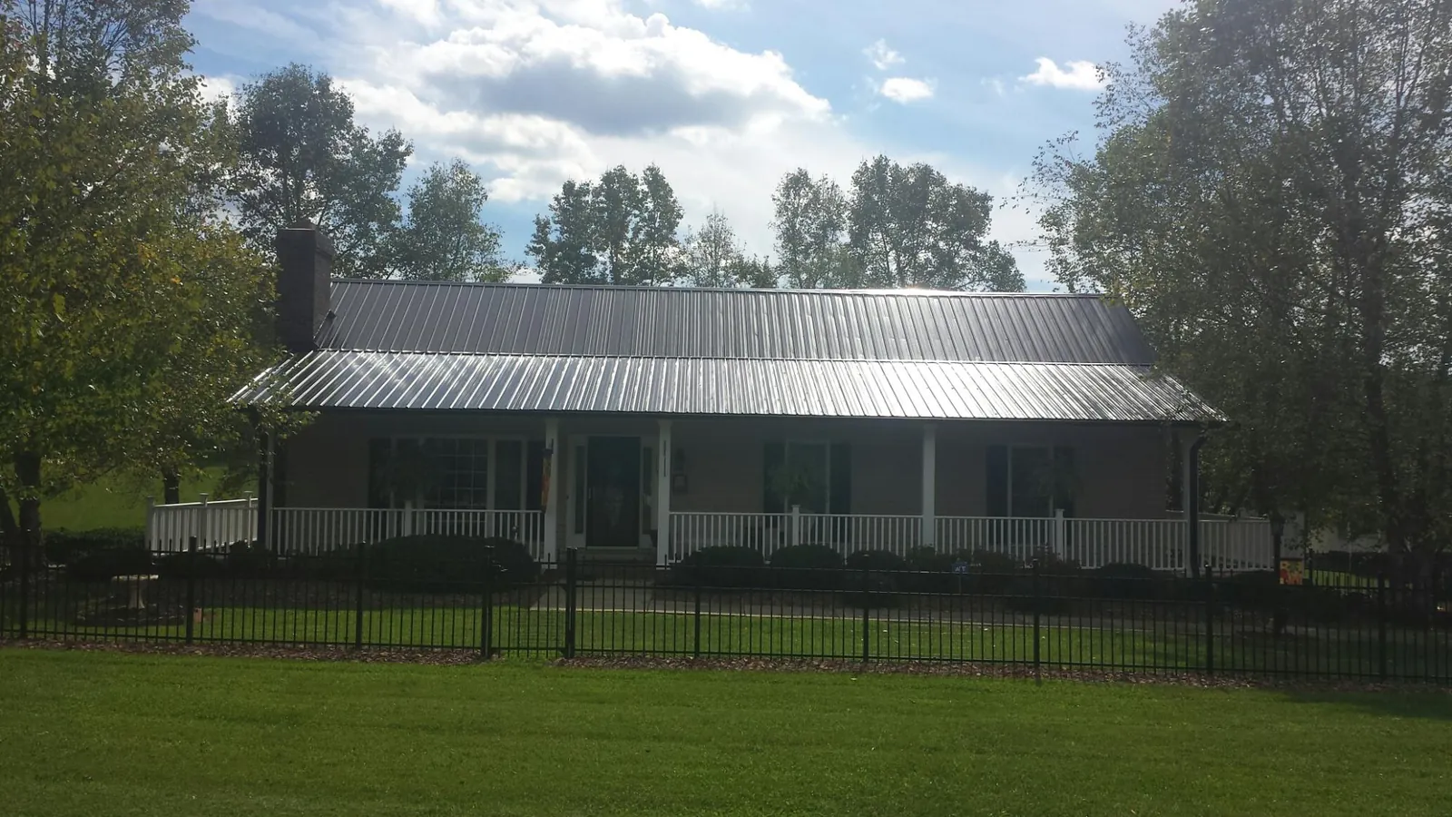 Gray metal roof on a brick ranch with a full width front porch — Gutter Guard Installation work by our crew in Hagarville