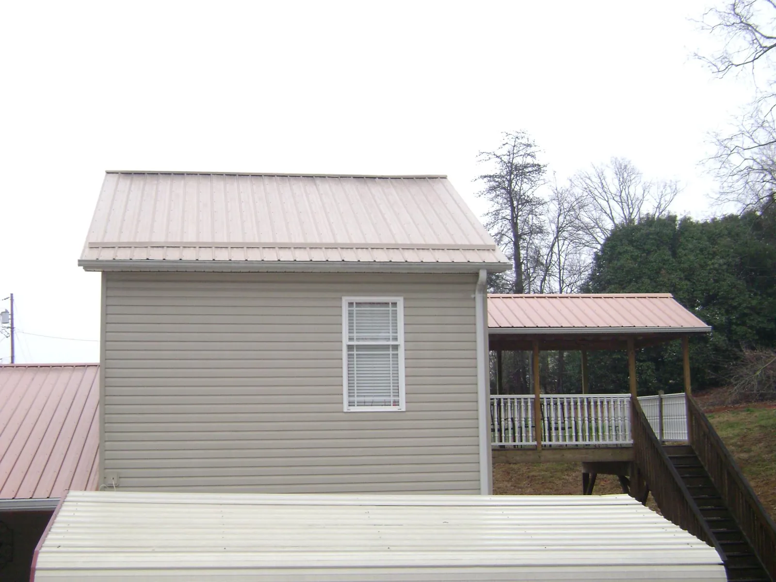 Tan metal roofs on a two story addition and attached porch, from a Roof Replacement job in Hagarville