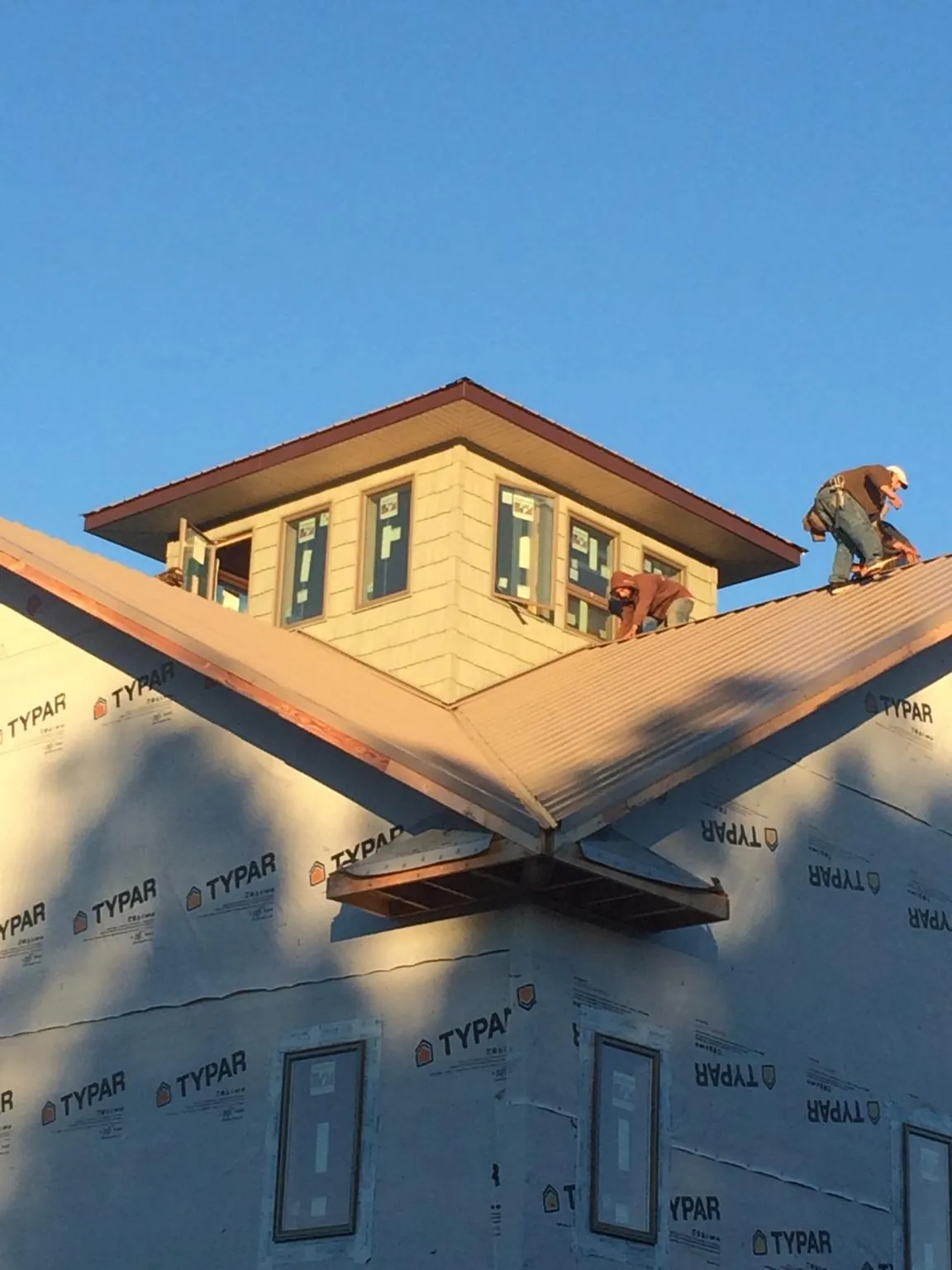 Roofers working around a rooftop cupola on a new metal roof at sunset — Roof Waterproofing in Hagarville by Roofing Brothers